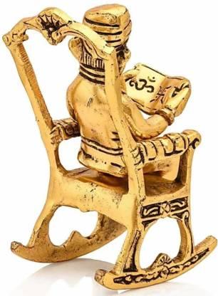 Gold figurine of a seated figure with a book on a white background