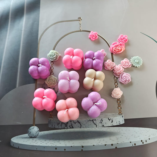 Colorful flower-shaped candles on a decorative stand with a neutral background