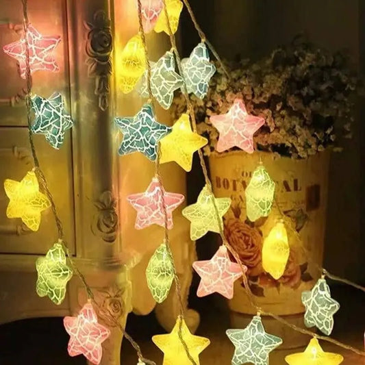 String of colorful star-shaped lights on a wooden surface with a blurred background.