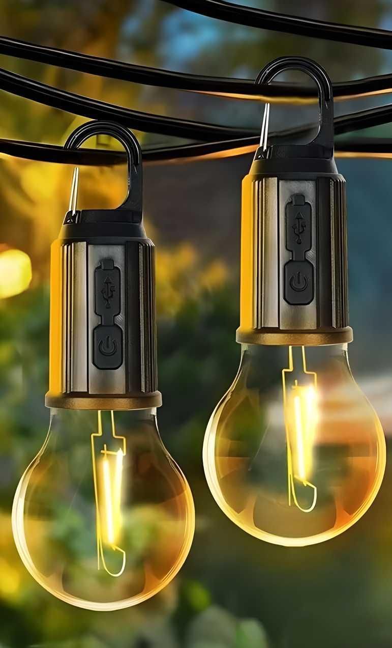 Two illuminated outdoor string lights with visible wiring against a blurred natural background.