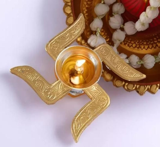 Decorative gold oil lamp with a lit candle on a white background