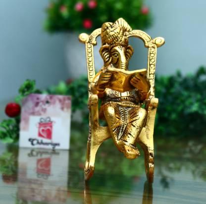 Gold-colored statue of a seated figure on a chair with a blurred background
