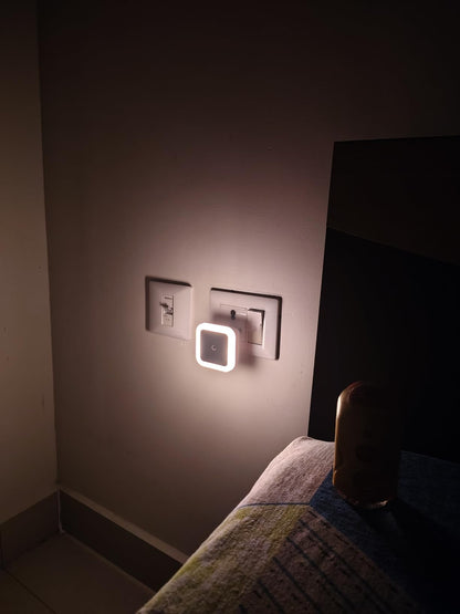 Square wall light fixture on a dark wall next to a bed