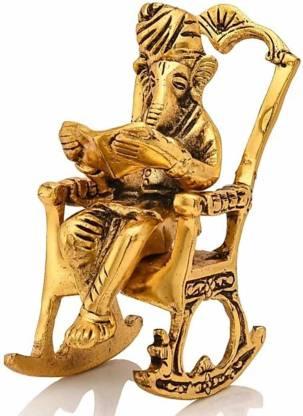 Gold-colored statue of a seated figure with a staff on a white background