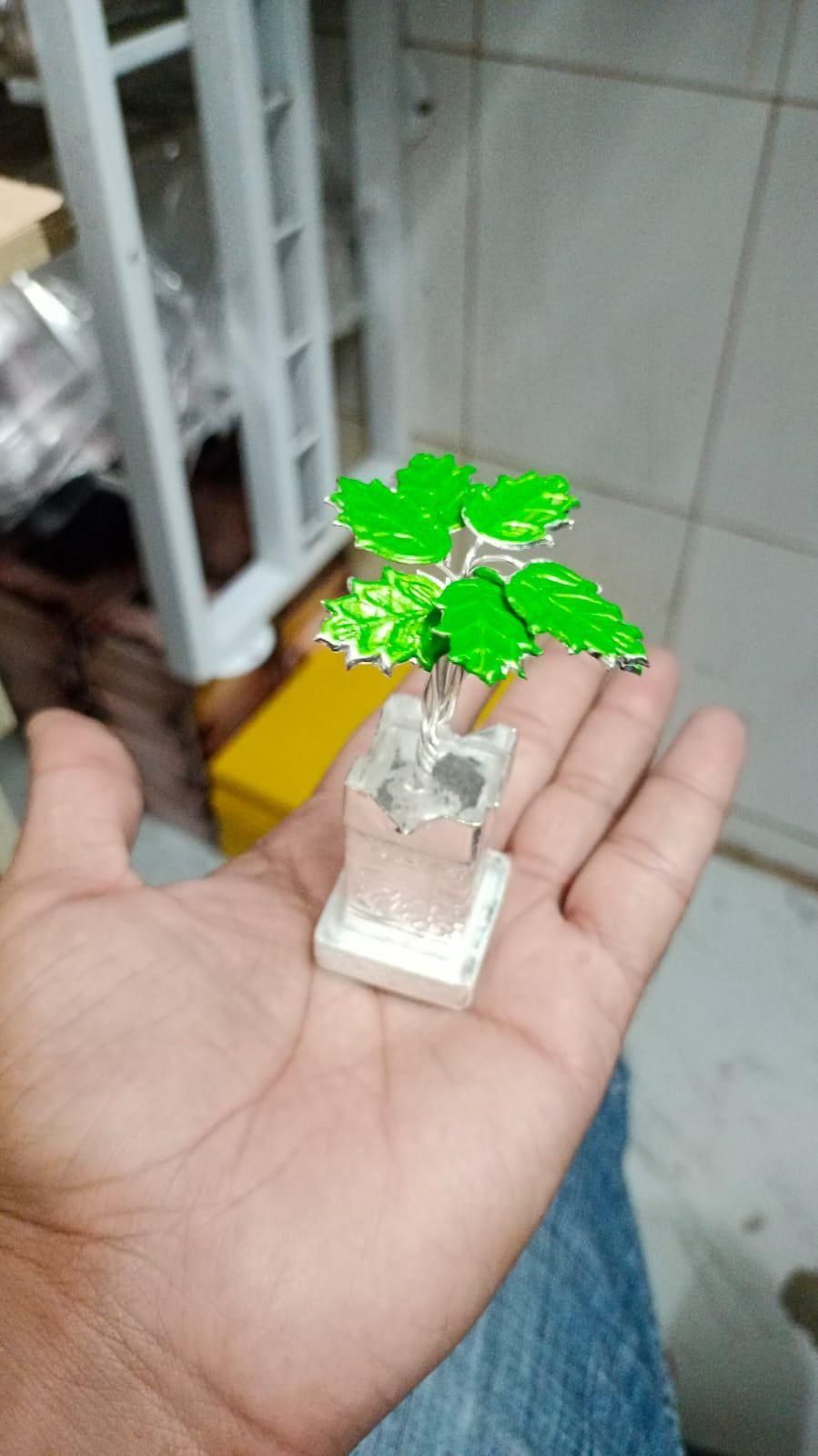 Small decorative plant figure held in a hand with a blurred background
