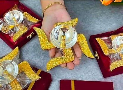 Hand holding a decorative item with gold and red packaging on a gray surface