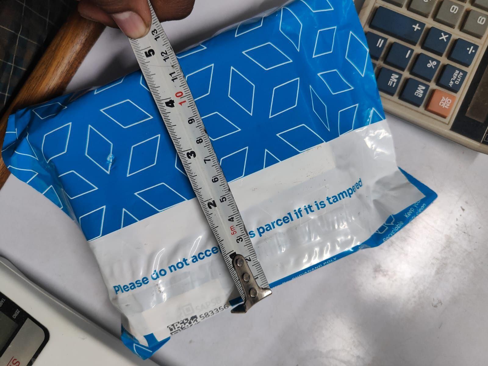 Blue and white parcel with a ruler for scale on a desk