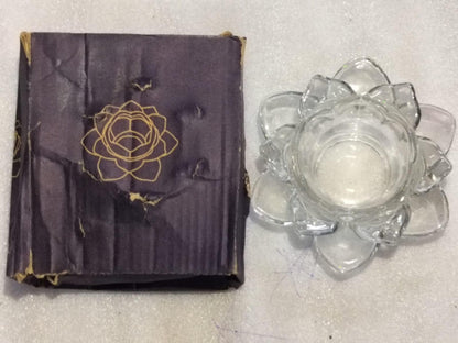 Purple fabric with gold floral design and clear glass flower-shaped container on a light gray surface
