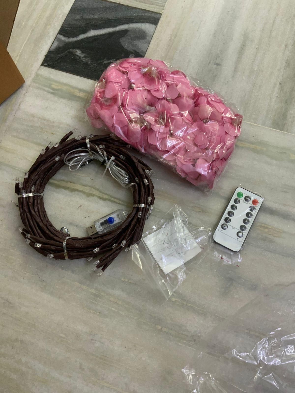 Pink flower petals, brown wire coil, remote control on a marble surface