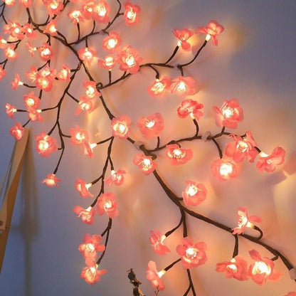 Decorative string lights shaped like cherry blossom branches with pink flowers and warm white bulbs.