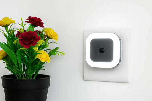 Smart home device on a wall next to a potted plant with flowers.