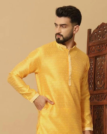 Man wearing a yellow kurta against a beige background