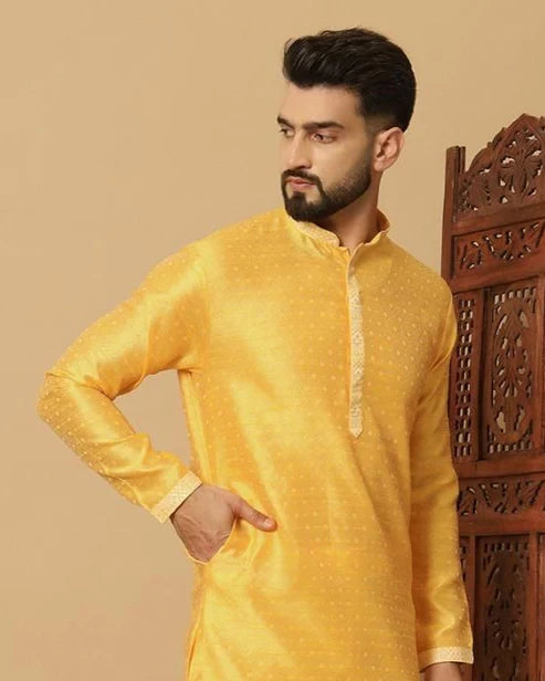 Man wearing a yellow kurta against a beige background