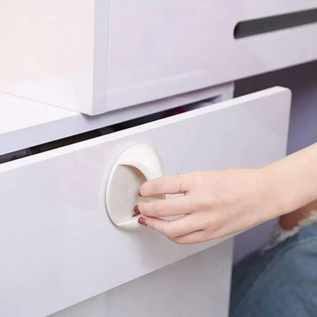Hand reaching for a cabinet handle with a protective cover on a white cabinet.