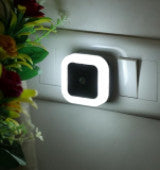 Small LED light device on a white surface with flowers in the background